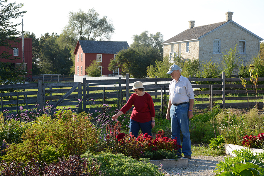 older couple stands in a garden looking at flowers