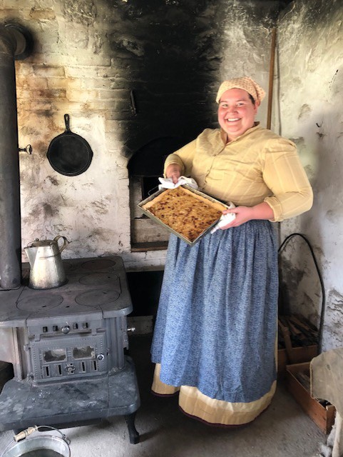 A woman shows the item she baked in a historic oven as part of her employment at Old World Wisconsin!