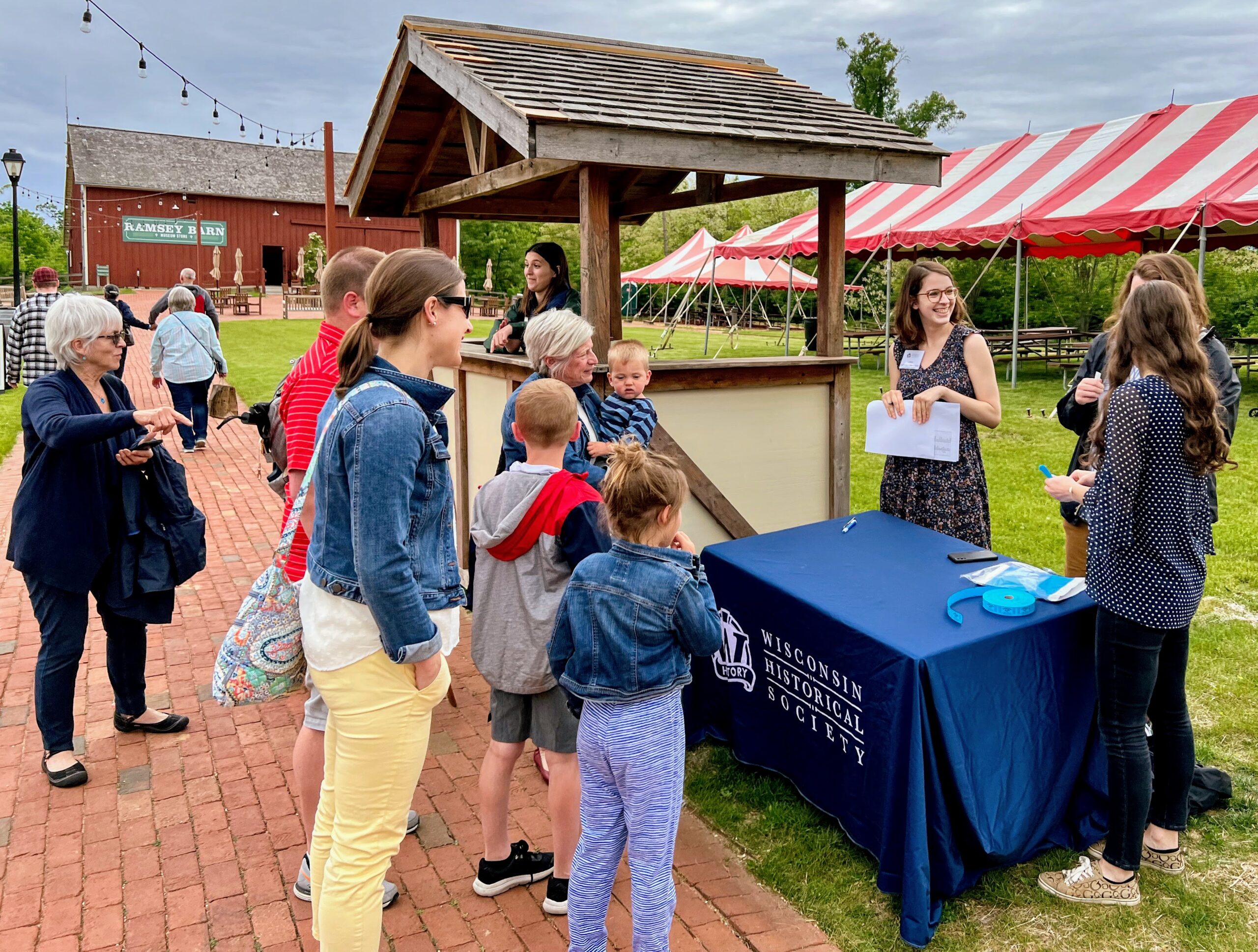 A group of people gathered near a Wisconsin Historical Society booth outside of the Ramsey Barn