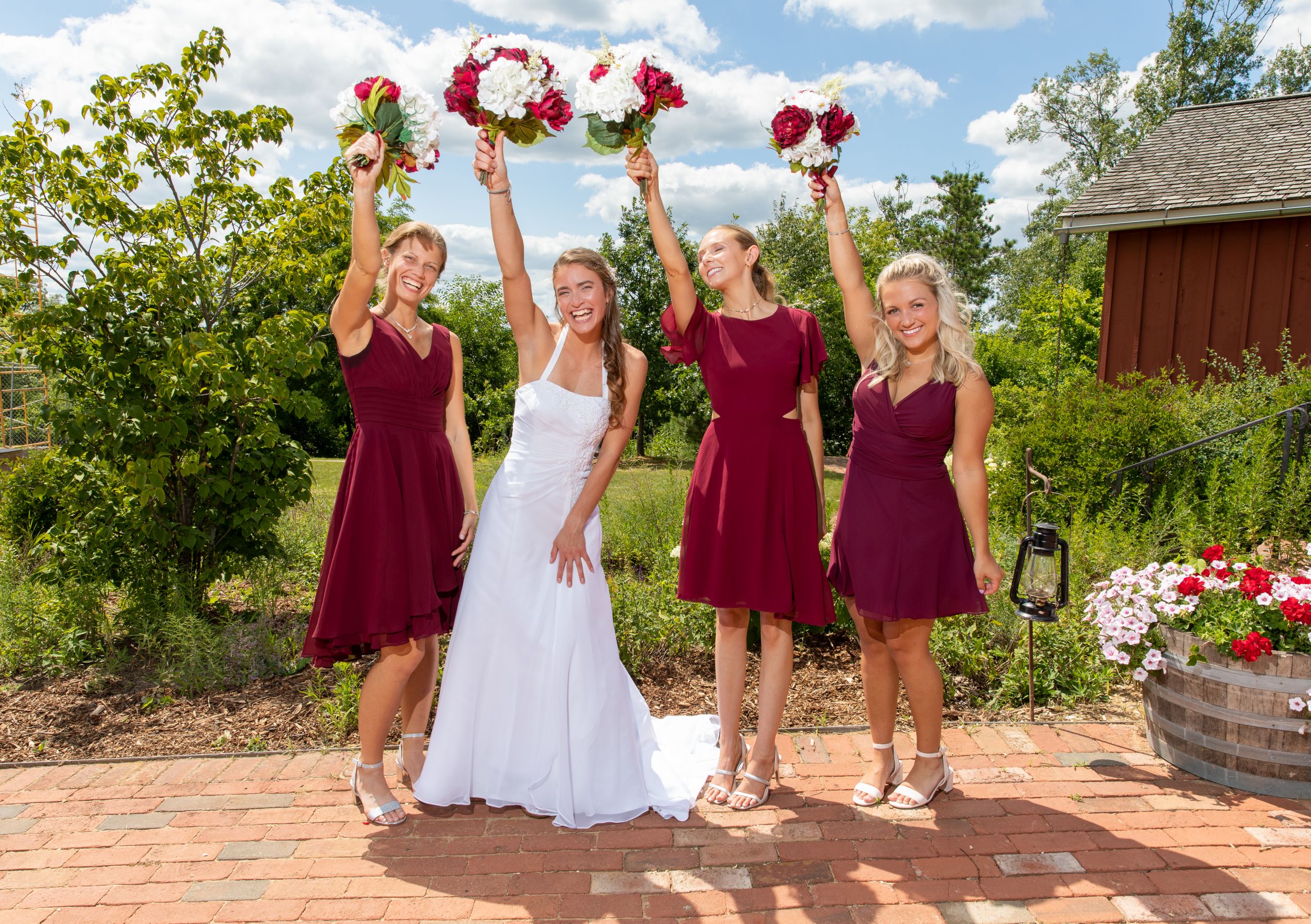 A bride and her three bridesmaids, dressed in dark red, with their flower bouquet's.