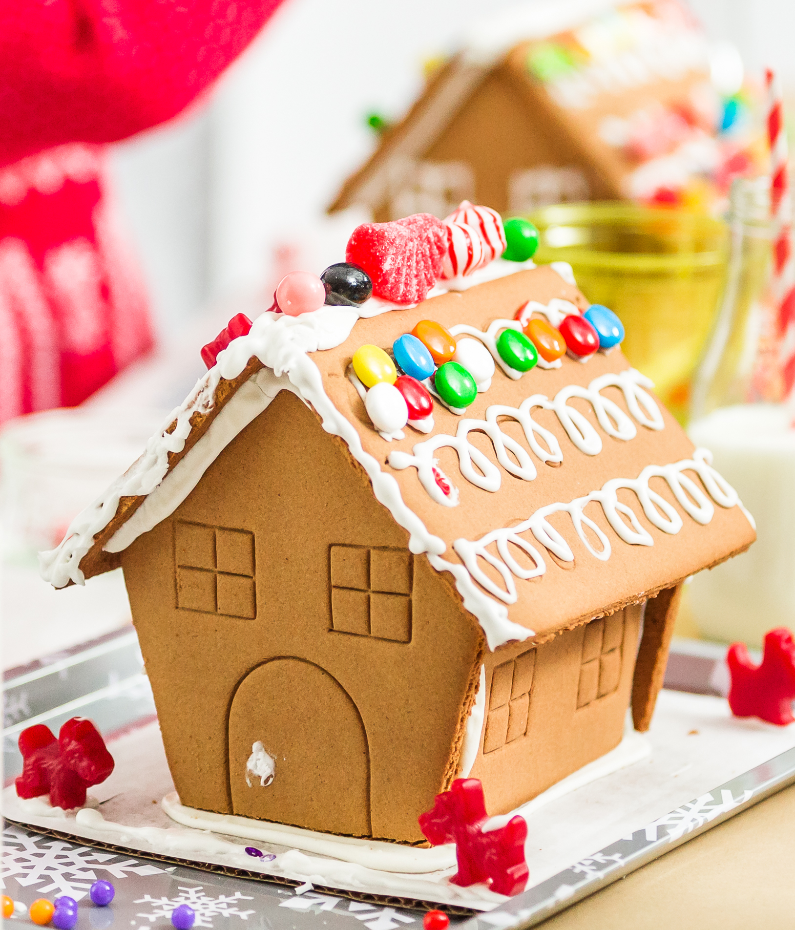 A gingerbread house decorated with white icing, red, yellow, green, blue and orange candy